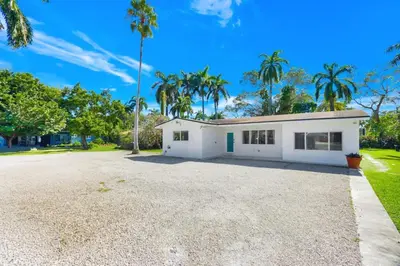 a white house with palm trees in the background at Spacious Miami 4BR Retreat with Pool & BBQ in Miami