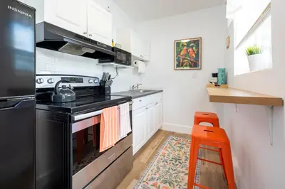 a kitchen with a black stove and a stool at Tropical Retreat with Private Yard, Fire Pit, Hammock in Hollywood