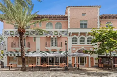 a large pink building with tables and a palm tree at Kasa El Paseo Miami Beach in Miami Beach