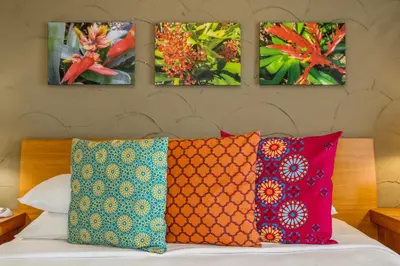 a bed with four paintings on the wall and four pillows at Kasa El Paseo Miami Beach in Miami Beach