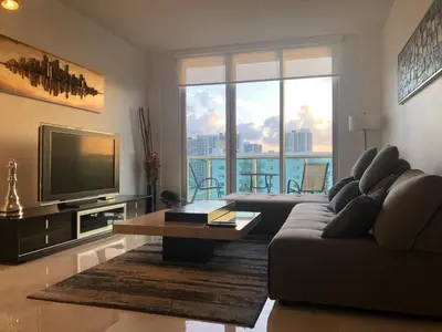 a living room with a couch and a television at Penthouse Ocean Reserve in Miami Beach