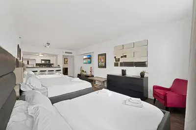 a hotel room with two beds and a red chair at Casa Grande Suites on Ocean Drive in Miami Beach