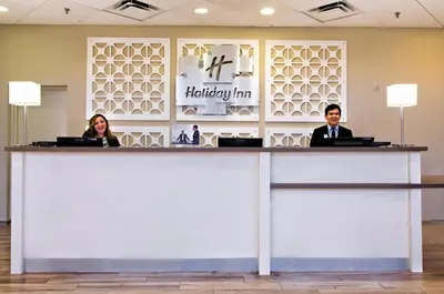 two people sitting at a reception counter in a hotel lobby at Holiday Inn Miami West - Airport Area by IHG in Hialeah Gardens