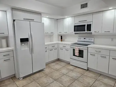 a white kitchen with white cabinets and a refrigerator at Castle Beach Club Apartments in Miami Beach