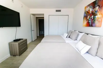 a bedroom with two beds and a flat screen tv at Beachwalk Resort Residence in Hollywood