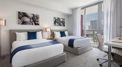 a hotel room with two beds and a desk and a desk at Beachwalk Resort Residence in Hollywood