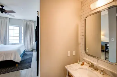 a bathroom with a bed and a sink and a mirror at The Plymouth South Beach in Miami Beach