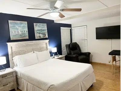 a bedroom with a white bed and a black chair at Harmonious Suites in North Miami Beach