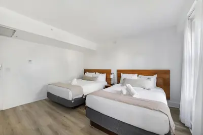 two beds in a room with white walls and wooden floors at The Meridian Hotel by At Mine Hospitality in Miami Beach