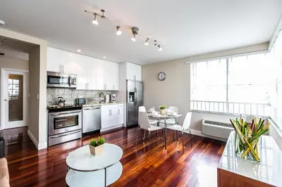 a kitchen with white cabinets and a wooden floor at Hudson Apartments in Miami Beach