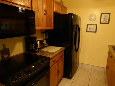 a kitchen with a black refrigerator and wooden cabinets at PlayaBlanco Suites in Fort Lauderdale