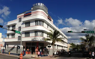 a white building with a sign on the side of it at Sherbrooke All Suites Hotel in Miami Beach
