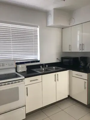 a kitchen with white cabinets and a sink and a window at Beach Place Hotel in Miami Beach