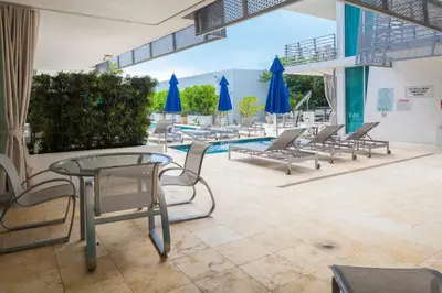 a pool with chairs and tables and blue umbrellas at SBV Luxury Ocean Hotel Suites in Miami Beach