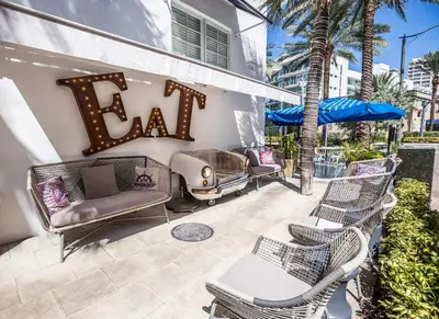 a patio with chairs and a sign that reads eat at Oceanside Hotel and Suites in Miami Beach