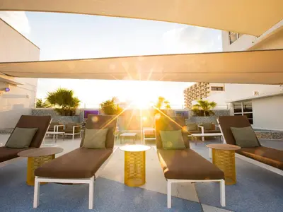 a patio with chairs and tables and the sun shining at Clevelander Hotel in Miami Beach