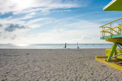 a beach with a lifeguard tower and people on the beach at Parisian Hotel in Miami Beach