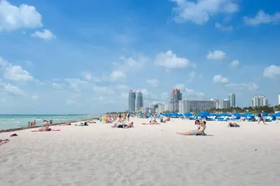 a group of people sitting on a beach at Parisian Hotel in Miami Beach