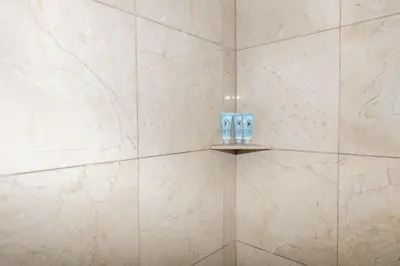 a bathroom with white marble walls and a shelf with two toilets at Parisian Hotel in Miami Beach