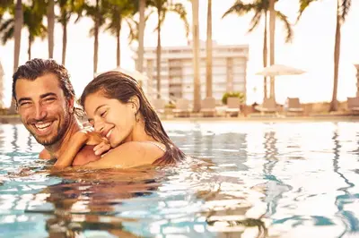 a man and a woman swimming in a swimming pool at Four Seasons Hotel Miami in Miami