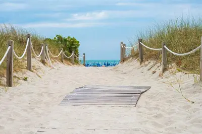 a wooden path through the sand on a beach at Geneva Hotel in Miami Beach