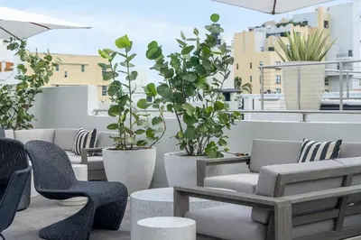 a row of chairs and tables on a balcony with plants at Nassau Suite South Beach, an All Suite Hotel in Miami Beach