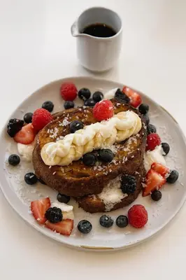 a plate of pancakes with berries and a cup of coffee at Nassau Suite South Beach, an All Suite Hotel in Miami Beach