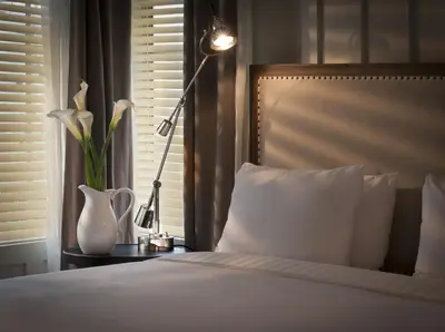 a bedroom with a bed and a lamp and a vase with flowers at Shepley South Beach Hotel in Miami Beach
