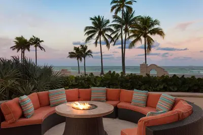 a patio with a couch and a table and palm trees at Hollywood Beach Marriott in Hollywood