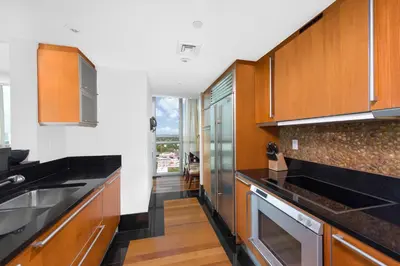 a kitchen with wooden cabinets and black counter tops at Oceanview Private Condo at The Setai -2402 in Miami Beach