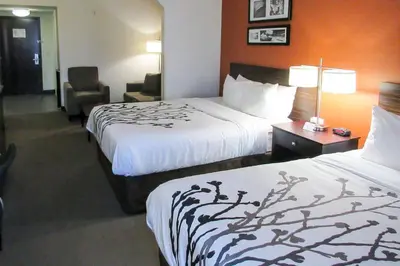 a hotel room with two beds and a chair at Sleep Inn & Suites Ft Lauderdale International Airport in Dania Beach