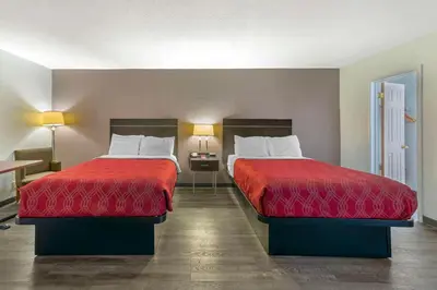 two beds with red covers in a hotel room at Fort Lauderdale Gardens Inn & Suites Ft Lauderdale International Airport in Hollywood