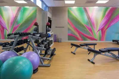 a gym with exercise equipment and a colorful mural at Sonesta Miami Airport in Miami