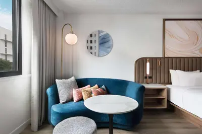 a living room with a blue couch and a bed at Sonesta Miami Airport in Miami