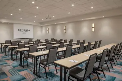 a conference room with tables and chairs and a screen at Sonesta Miami Airport in Miami