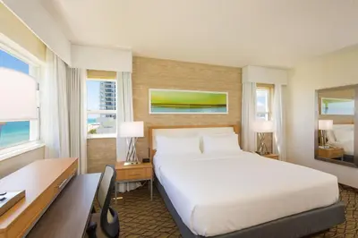 a hotel room with a bed and a desk and windows at Holiday Inn Miami Beach-Oceanfront by IHG in Miami Beach