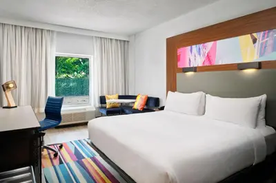 a hotel room with a large bed and a desk at Aloft Miami Dadeland in Kendall