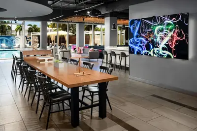 a dining room with a large wooden table and chairs at Aloft Miami Dadeland in Kendall
