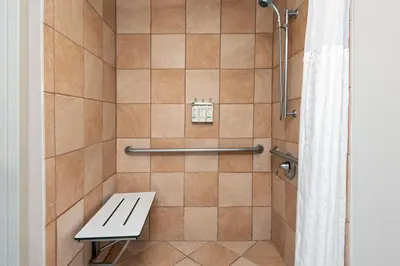 a shower with a bench in a bathroom at Holiday Inn Express Miami Airport Doral Area by IHG in Miami