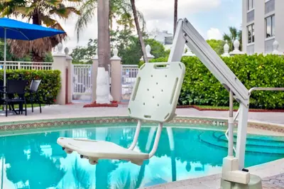 a white chair sitting next to a swimming pool at Holiday Inn Express Miami Airport Doral Area by IHG in Miami