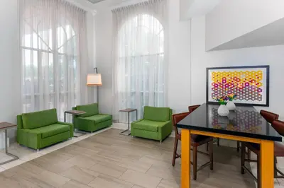 a waiting room with green chairs and a painting at Holiday Inn Express Miami Airport Doral Area by IHG in Miami