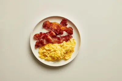 a white plate with scrambled eggs and bacon on it at Holiday Inn Miami-Doral Area by IHG in Miami