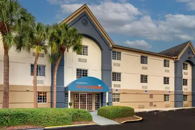 a hotel with palm trees in front of a building at Sonesta Simply Suites Miami Airport Doral in Miami