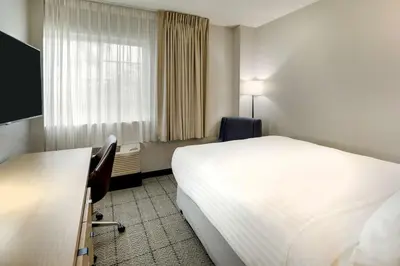 a hotel room with a bed and a desk and a window at Sonesta Simply Suites Miami Airport Doral in Miami
