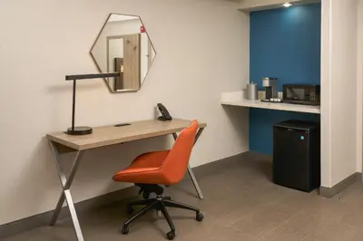 a desk with a mirror and a chair in a room at Holiday Inn Express Hotel & Suites Kendall East-Miami by IHG in Kendall