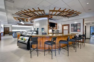 an office lobby with a bar with black chairs at Hyatt Place Miami Airport-West/Doral in Miami