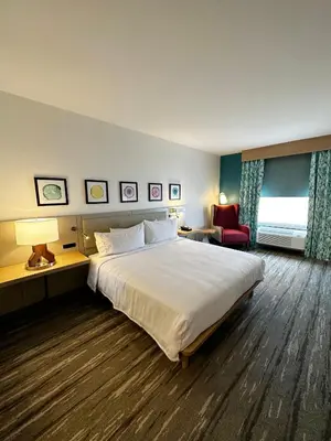 a hotel room with a large bed and a red chair at Hilton Garden Inn Miami Airport West in Miami