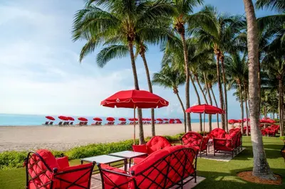 a table with red chairs and umbrellas on the beach at Acqualina Resort and Residences in Miami Beach