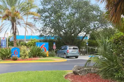 a van parked in a parking lot with a tree at Motel 6-Cutler Bay, FL in Cutler Bay