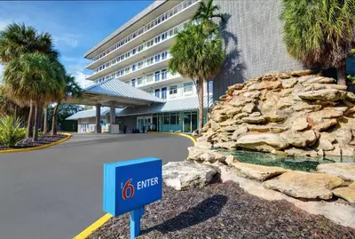 a sign in front of a building with palm trees at Motel 6-Cutler Bay, FL in Cutler Bay